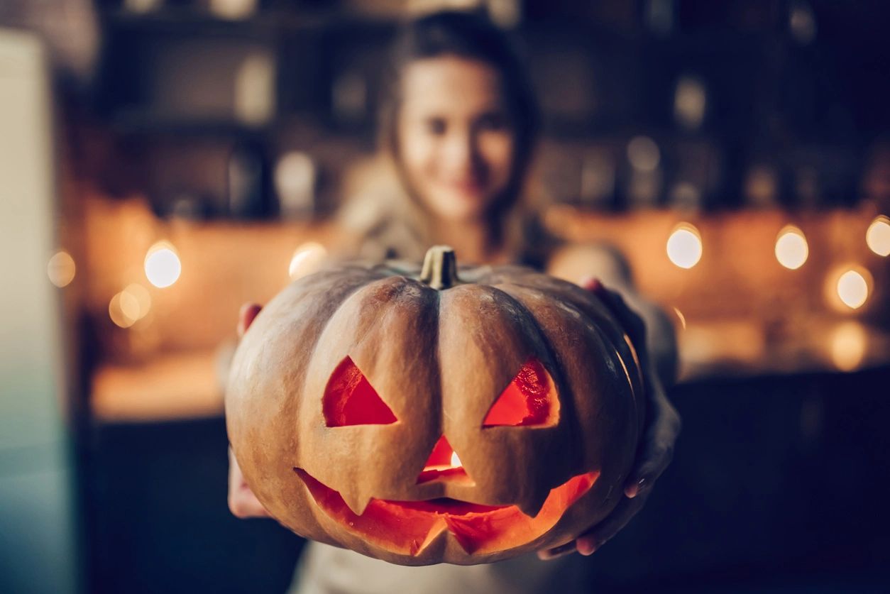 Child holding a lit jack 'o lantern style pumpkin